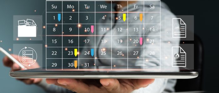 Event planners use timetables and agendas to arrange and schedule events. On the office table, a businessman is using his mobile phone and taking notes on the calendar desk.